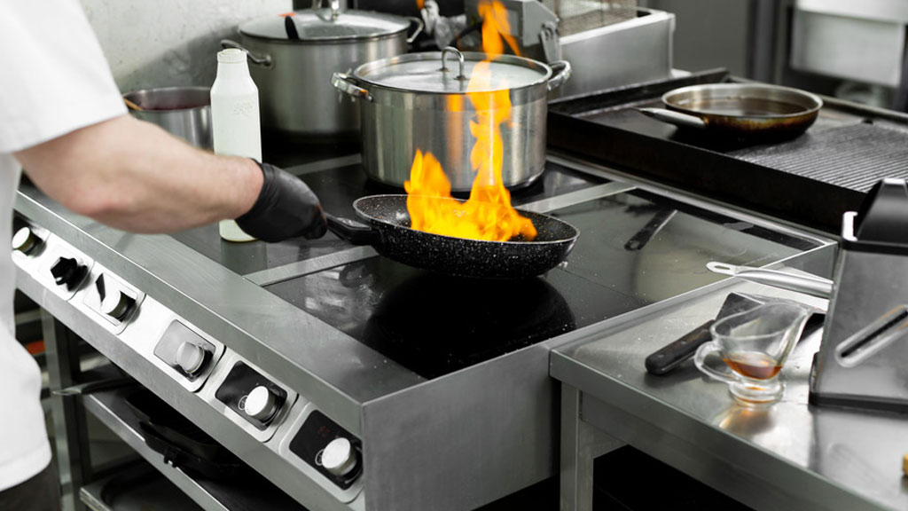 Chef cuisinant sur un piano de cuisson au gaz propane en cuisine professionnelle